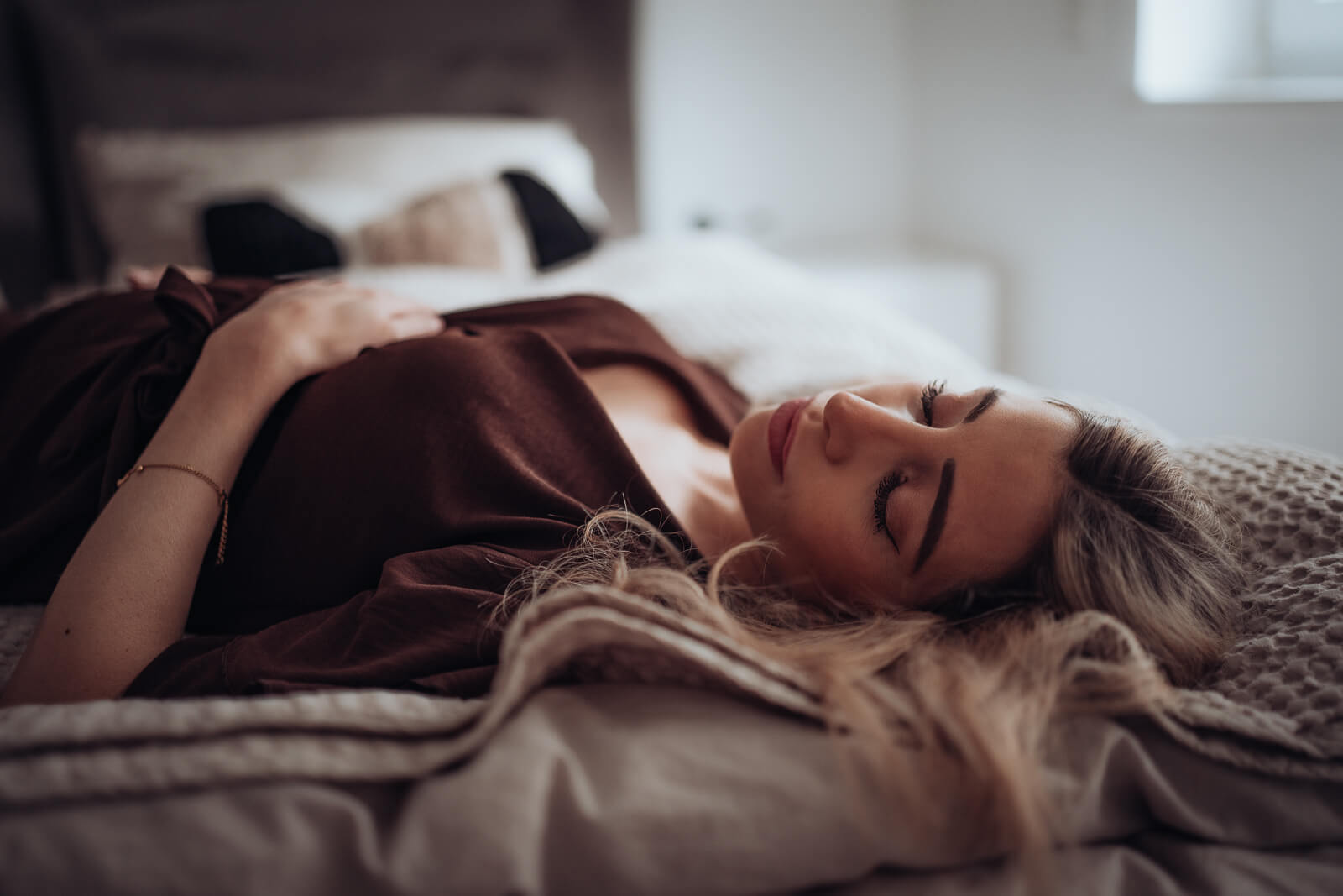 Homestory eines Babybauchshootings, bei dem die Schwangere auf dem Rücken im Bett liegt und mit geschlossenen Augen die Bewegungen ihres Babys im Bauch spürt.