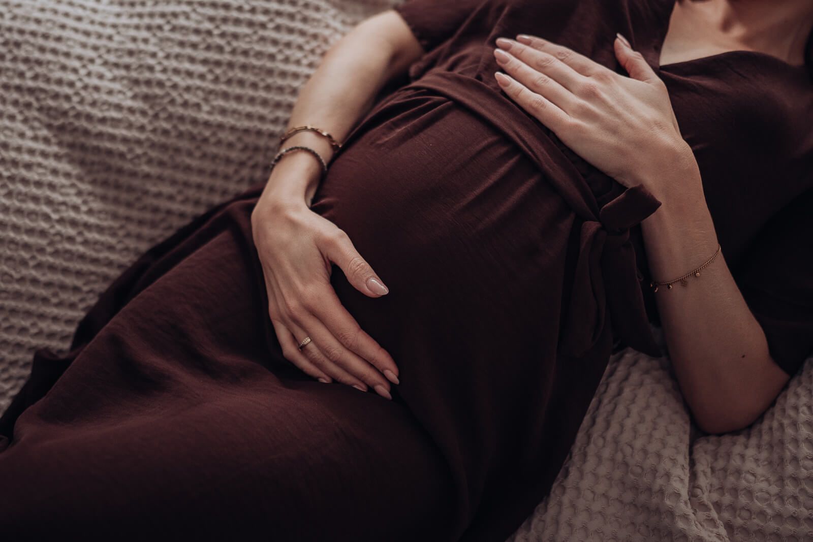 Detailbild eines  Babybauchs von oben, während die Schwangere auf dem Bett liegt.