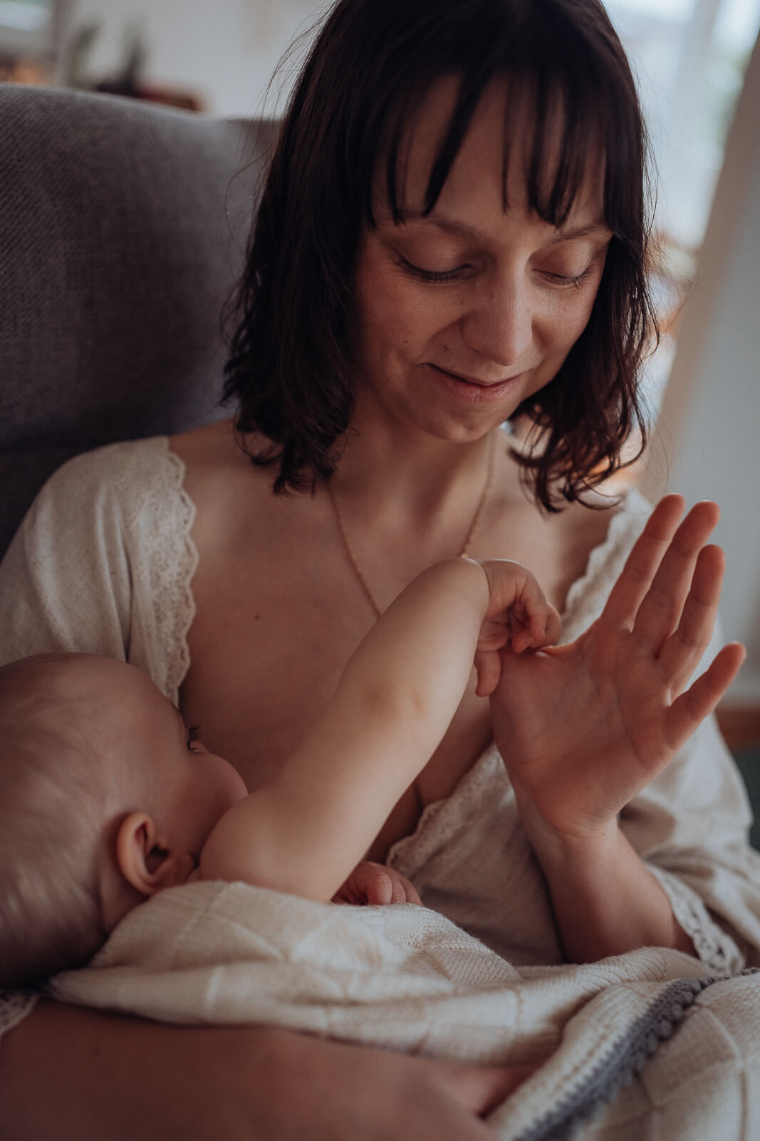 Während des Stillens spielt ein Baby mit den Fingern der Mama.