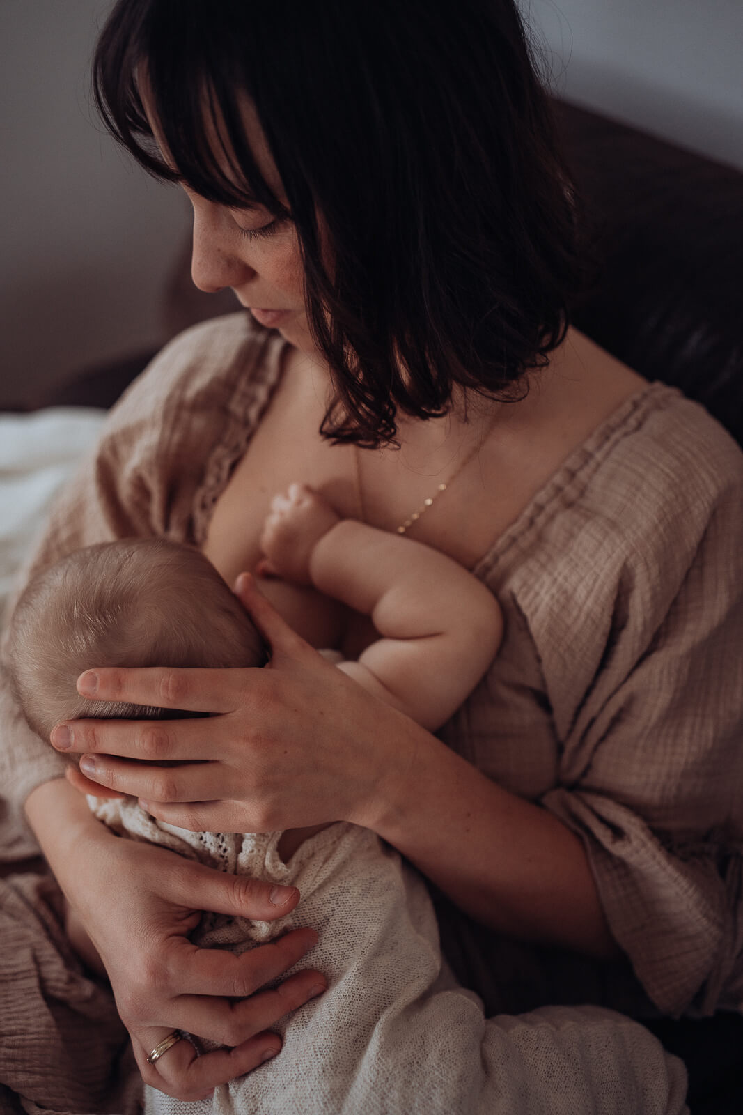 Stillmoment zwischen Mama und Baby mit liebevollem Blick der Mama zu ihrem Baby im Schoß.