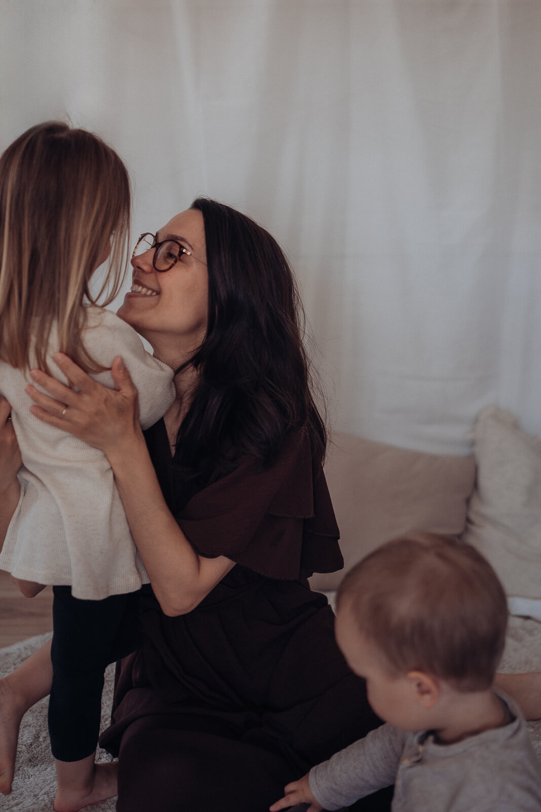 Babybauch und Motherhood Fotografin Sarah Bomm hält ihre Tochter im Arm und schaut sie lächelnd und voller Liebe an.