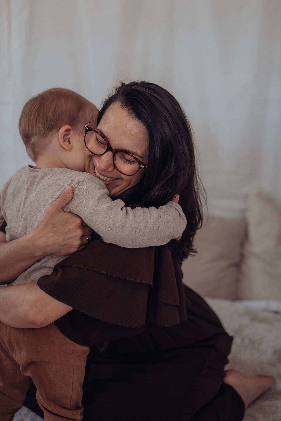 Babybauch und Motherhood Fotografin Sarah Bomm umarmt liebevoll ihren Sohn, der sie ebenfalls umarmt.