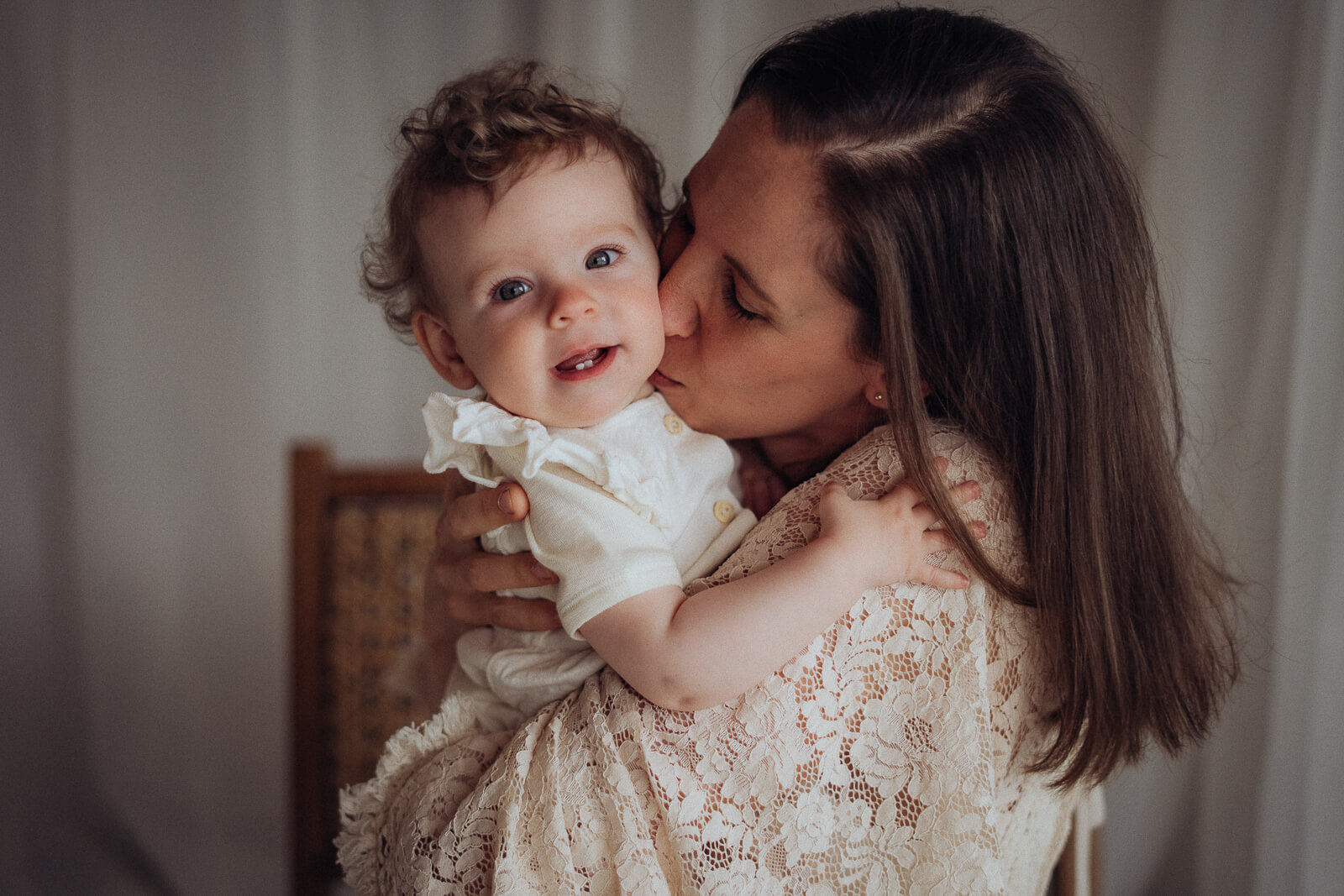 Mama hält ihr Baby auf dem Arm und drückt ihm liebevoll einen Kuss auf die Wange.