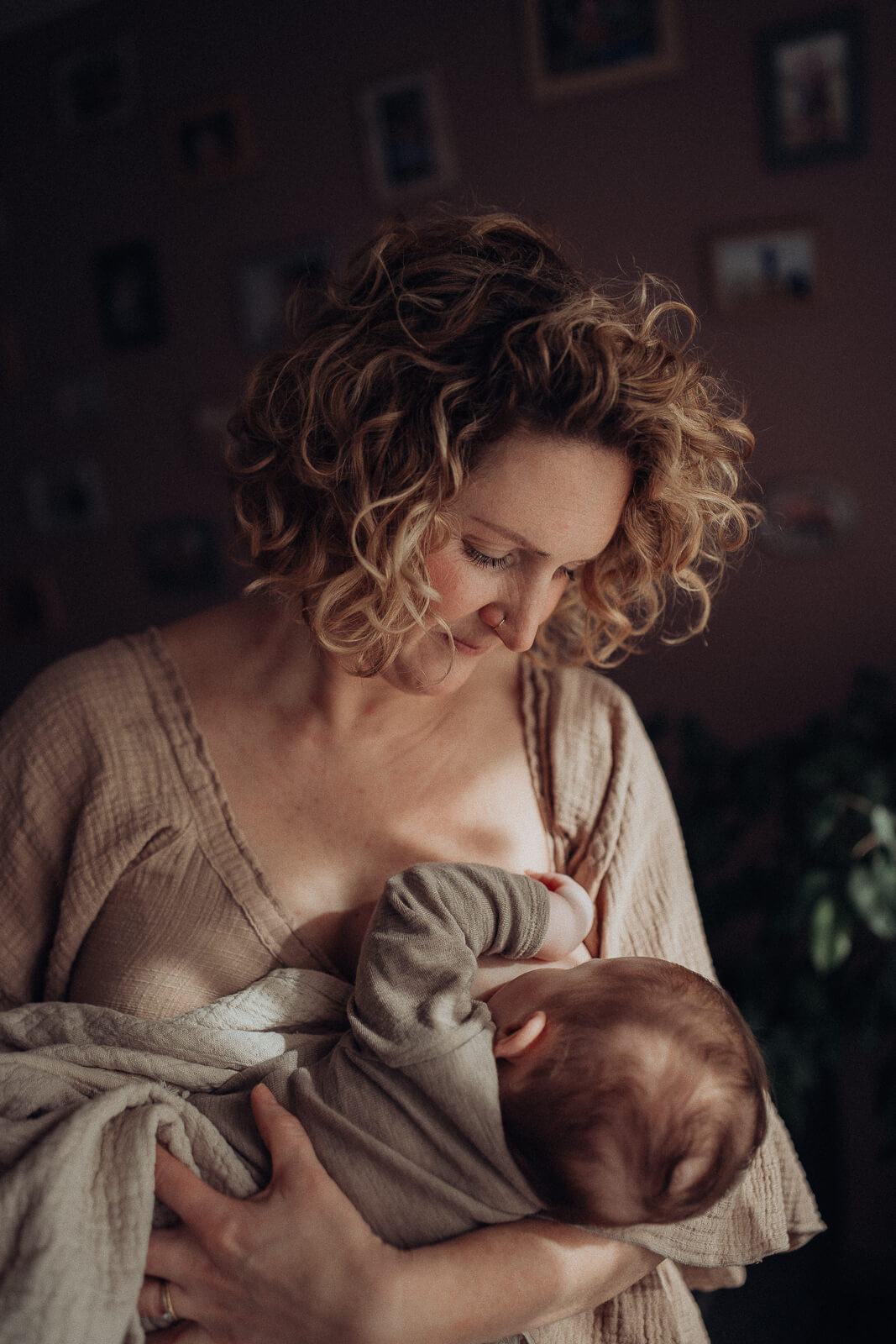 Stillmomente der Motherhood Reise, Mama hält dabei ihr Baby im Arm und steht im Wohnzimmer.